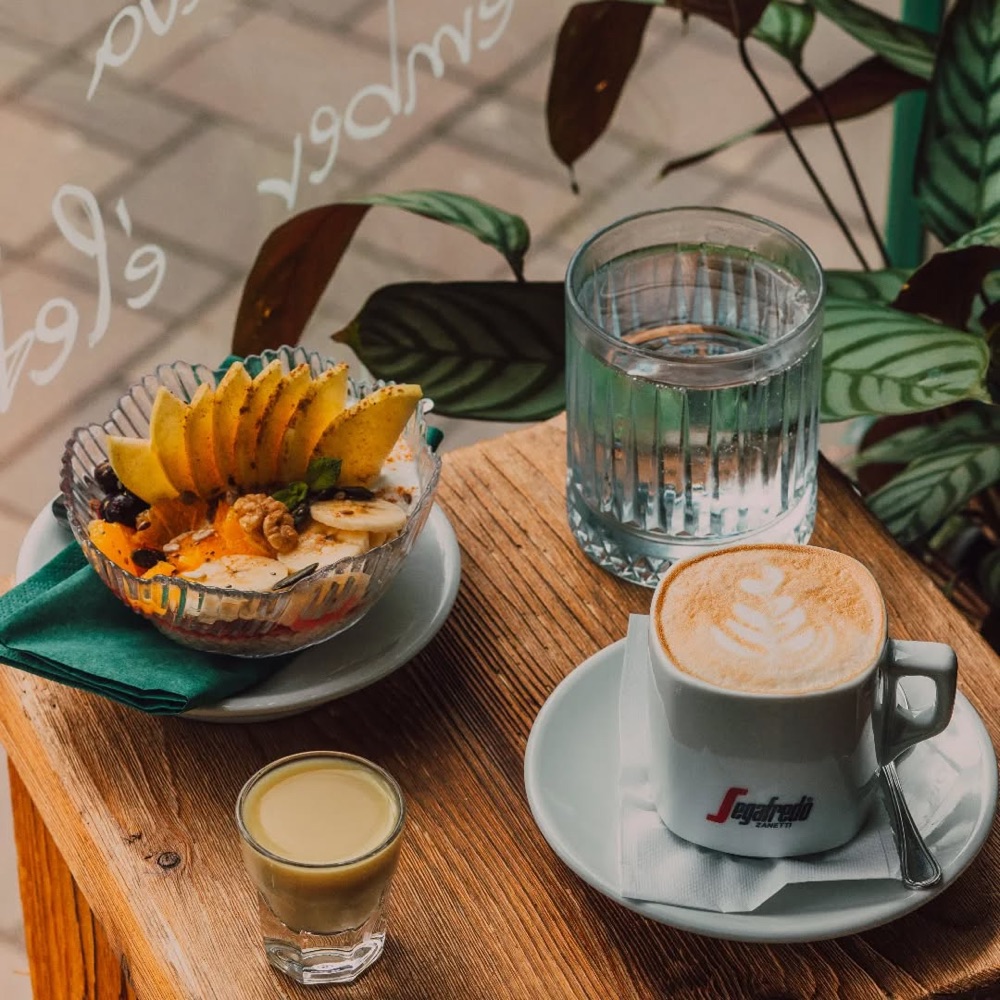 Reggeli tál friss gyümölccsel és cappuccino a presszó teraszasztalán